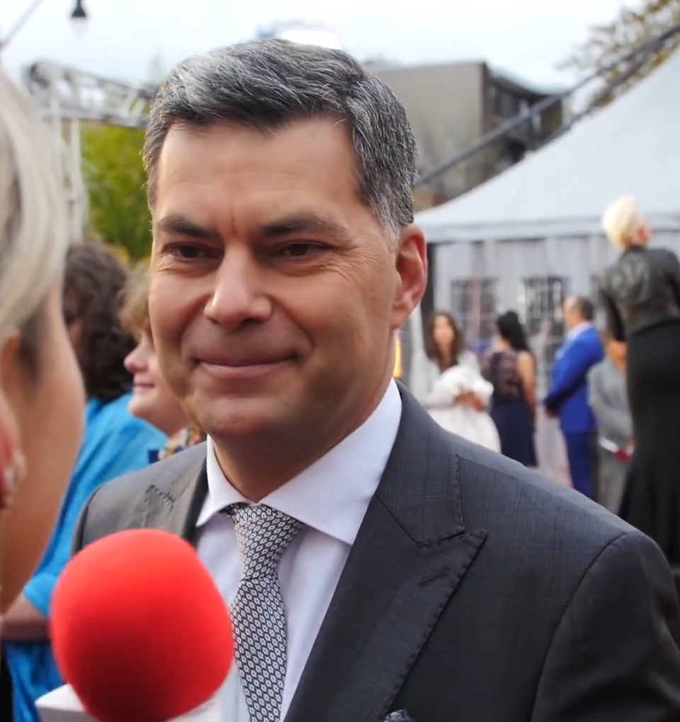 Man smilling at a person holding a red microphone.
