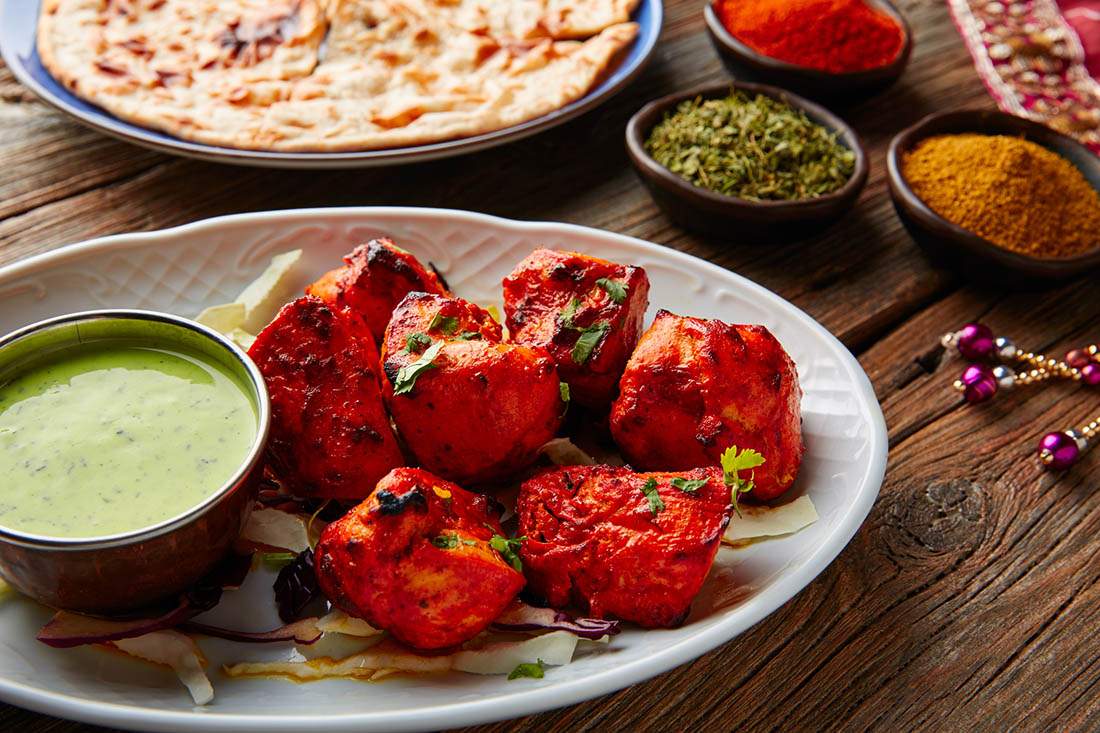 Red chicken pieces alongside a green dip
