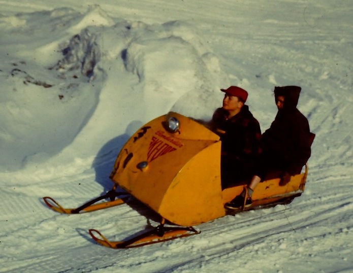 Photo of two poeple riding a Ski-Doo over snow