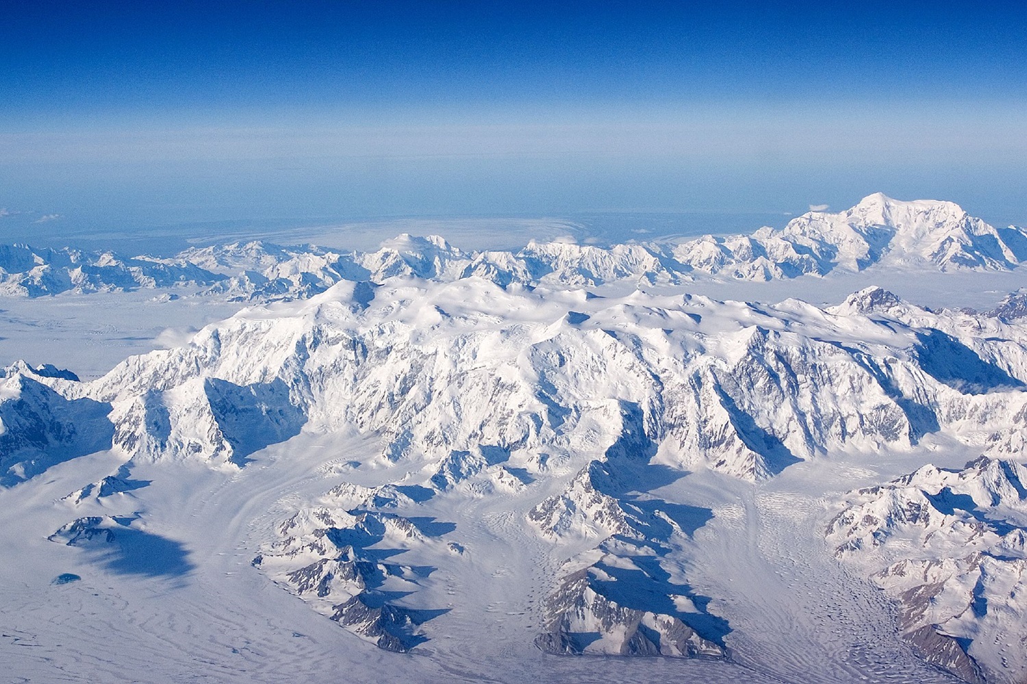 Areal shot of giant, snow-covered mountains.