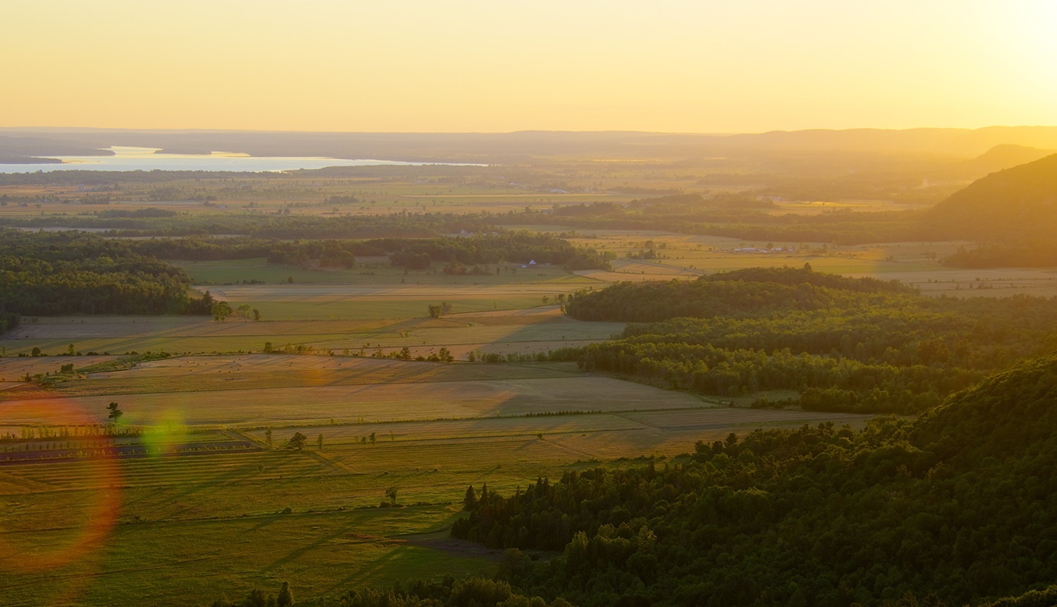 Coucher de soleil sur des champs agricoles.
